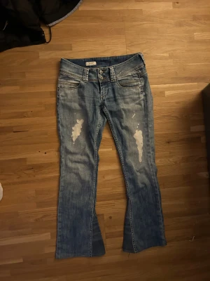 Bootcut Pepe jeans - blå jeans med slitningar och dubelknapp, omsydda till bootcut från Pepe Jeans. Så sjukt snygga men säljer pga de var för korta. W28, L32. Midjemått: 38cm, innerbenslängd: 70-71cm. Står inte storlek men skulle gissa s-m?
