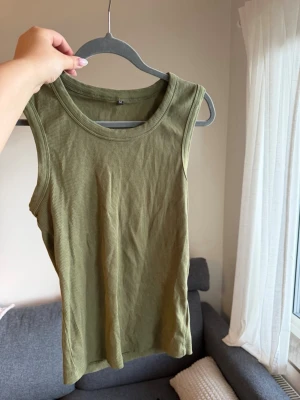 Olivgrön ribbad t-shirt - Snygg olivgrön ribbad t-shirt. Perfekt till jeans eller kjol och har en rund halsringning. Materialet är stretchigt och mjukt, vilket gör den bekväm att bära hela dagen.