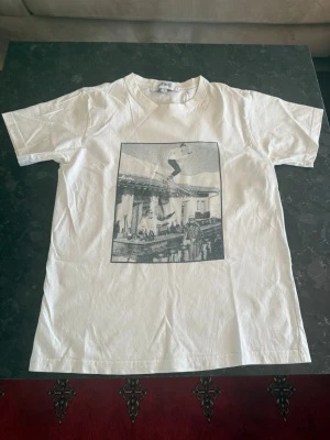 2 st Vit t-shirt från Fiore Studios - 2 riktigt snygga t shirt med tryck på framsida, den med skid gubben har en liten fläck bak knappt synlig, bild på den finns. Den andra har ibga defekter eller fläckar båda är storlek S  250 för båda