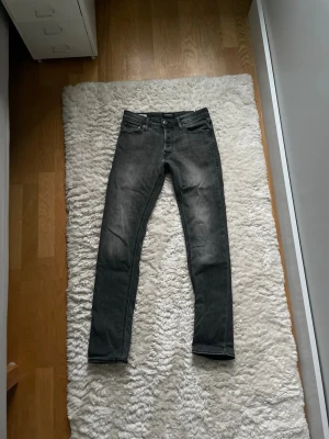 Svarta Jack and Jones jeans - Snygga svarta slim fit jeans med lätt tvättad look och klassisk femficksdesign. Jeansen har smal passform och normal midja, perfekta till en avslappnad stil. Materialet är troligtvis bomull med lite stretch för extra komfort.