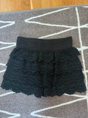 Svart spetsshorts - Fina svarta shorts i spets med flera lager säljes. Storlek XS. Några knappt märkbara tecken på användning – syns på bilderna – men i övrigt i utmärkt skick! 🤍 