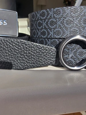 Calvin Clein & BOSS skärp med metallspänne - Snyggt svart bälte från BOSS med präglad struktur och ett stilrent metallspänne. Bältet har en diskret logga och passar perfekt till jeans eller kostymbyxor. Klassisk design med modern touch. 500kr per bälte.