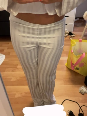 Vitrandig satinpyjamas byxor - Säljer en snygg tvådelad pyjamas i satin med vita ränder. Detta är annonsen för ENDAST byxorna. hela settet säljs i en annons på min profil. otroligt sköna och väldigt mjukt material. 