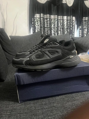 Svarta Dior sneakers med reflekterande detaljer - Snygga svarta Dior B30 sneakers med reflekterande detaljer på sidorna och meshpaneler för extra ventilation. Skorna har en chunky sula och klassisk snörning. Perfekta för dig som vill ha en modern och exklusiv look. Pris kan diskuteras tveka inte med att skicka förslag eller skicka meddelande