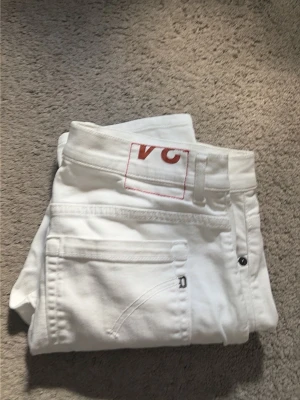 Dondup george jeans - Snygga vita jeans från dondup med röd broderad logga på bakfickan. Klassisk femficksmodell med raka ben och bälteshällor. Perfekta för en clean och fräsch look. Materialet är bomull med lite stretch för extra komfort.