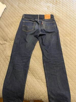 Mörkblå Levi's jeans 501 (raka ben) - Säljer ett par mörkblå Levi’s 501-jeans i färgen Dark Indigo. Storlek: 32/32.  Jeansen är använda men i bra skick utan någon slitage. Nypris: ca 1 100 kr.