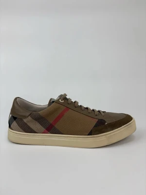 Burberry rutiga sneakers i beige - Snygga sneakers från Burberry med klassiskt rutigt mönster i beige, brunt, svart och rött. Skorna har lågt skaft, ovandel i canvas och mockadetaljer samt beige sula. Perfekta för dig som vill ha en stilren och trendig look.