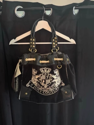 Juicy Couture väska - Jättefin vintage svart väska i velour med broderad logga. Använd men i mycket bra skick! Säljer den då den inte kommer till användning langre. Prutat och klart! Lite skavanker på sidan Modellen ar Juicy Couture Velour Daydreamer (Classic Crest) Köptes för 3500! Pris kan alltid diskuteras!