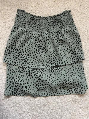 Grön kjol - Snygg grön kjol från ONLY med svart leopardmönster. Kjolen har en volangdetalj upptill och är tillverkad i ett lätt och skönt material. 