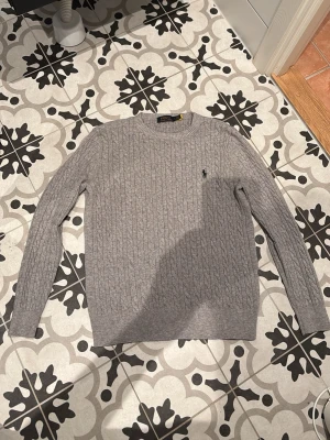 Polo Ralph Lauren Grey Cable Knit Sweater S 👕 - Classic Polo Ralph Lauren cable knit sweater in a versatile grey hue, featuring the iconic embroidered pony logo on the chest. This timeless piece offers a comfortable crew neck and a distinctive textured design, perfect for layering or standalone wear.  ⭐️ Condition : 8/10 🎲 Size : S 🎨 Color : Grey 📦 Fast and careful shipping.