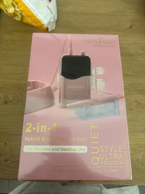 Miss Fancy Hybrid Nagelfil 2-i-1 - Elektrisk hybrid nagelfil från Miss Fancy Professional i rosa och svart. 2-i-1 design för både portabelt och stationärt bruk. Borstlös motor, tystgående och vibrationsfri. Perfekt för nagelvård och manikyr, med smart laddningssystem.