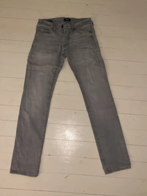 Ljusgrå slim/glenn jeans från Jack&Jones - Säljer ett par ljusgrå slim/glenn jeans i storlek 28/30. Jeansen har normal midja och är tillverkade i denim. Perfekta för en avslappnad och stilren look. Hör av er vid minsta fundering💯💯