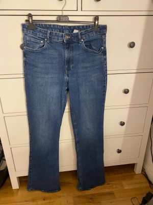 Blå bootcut jeans - Snygga blå bootcut jeans med hög midja. De är från HM och är i storlek 42. De är inte använda så mycket så dem är i ett väldigt fint skick. 