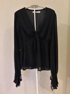 Svart blus - Jag säljer en svart V-ringad blus från NA-KD i storlek 32. Blusen har varit använd en gång och har inga defekter.