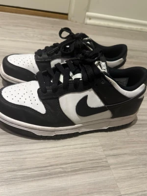 Nike Dunk Low svart/vit sneakers - Säljer ett par low nike panda dunks sneakers i svart och vitt. Skorna passar med alla typer av outfits, har används endast ett fåtal gånger men är i väldigt fint skick. Perfekta för dig som gillar stilrena och tidlösa sneakers.