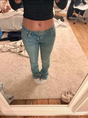 Ljusblå raka jeans med låg midja från mango - Säljer ett par ljusblå jeans med låg midja och raka ben. Jeansen har klassisk femficksdesign och stängs med dragkedja och knapp. Perfekta för en avslappnad och trendig look. Materialet är denim i bomull.