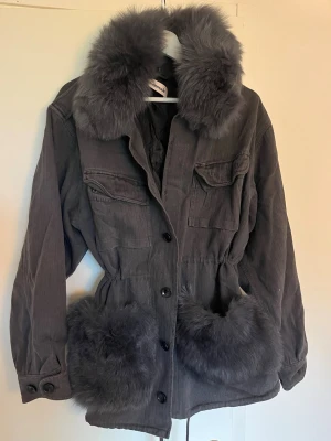 Grå pälsjacka från Custommade - Så fin grå pälsjacka från danska märket Custommade med stora fluffiga fuskpälsdetaljer vid krage och fickor. Jackan har knappar framtill, två bröstfickor med lock och dragsko midjan. Pälsen på kragen är avtagbar! Nypris 5700kr men säljs inte längre. Strl S/M. Jackan är sparsamt använd! 
