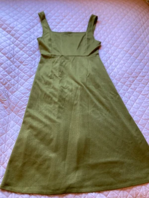 Apron dress - Grön apron dress. Var egentligen en T-shirt insydd men den klippte jag bort. Tror det är på ett ungefär storlek s. Klänningen är lite nopprig/ blir lätt nopprig 
