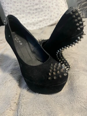 Svarta pumps med nitar från Trend - Svarta pumps i mockaimitation från Trend med höga platåklackar. Skorna är dekorerade med silvriga, konformade nitar över hela klacken, bakkappan och framtill. Ger en edgy och unik look som sticker ut.          (i’ve never used them since i bought them, they are not very wearable as they are old, more of a decorative piece to have)