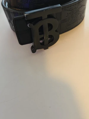 Svart Burberry bälte med monogramspänne - Bälte från burberry. Har änvänt lite men anars är den bra