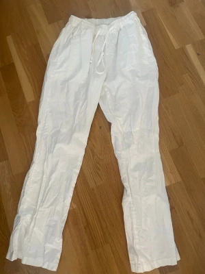 Vita linnebyxor från Madlady - Säljer ett par vita linnebyxor från Madlady i storlek XS/Short. Byxorna har resår i midjan med dragsko och raka ben. Tillverkade i ett lätt och luftigt linnematerial, perfekta för varma dagar. Två sidofickor för en avslappnad look.