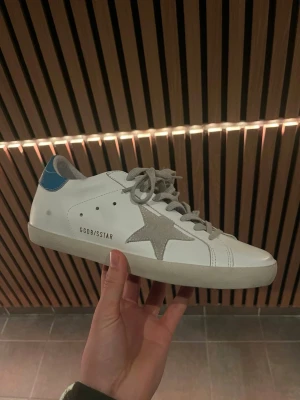 Golden Goose vita sneakers med blå detalj - Hej! Säljer nu dessa väldigt fräscha skor från golden goose || Det är i princip helt nya || box, dustbag och äkthets certifikat tillkommer || Hör av dig vid frågor eller funderingar!!🌟👏