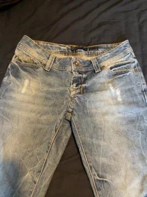 Ljusblå slitna jeans från Only - Säljer ett par ljusblå jeans från Only med slitningar och tvättade detaljer. Klassisk femficksmodell med dragkedja och knapp framtill. Jeansen har en smal passform och låg midja, perfekta för en avslappnad stil.