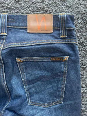 Premium Nudie Jeans | Grim Tim Org. Dry Navy – W32 L34 - Premium Grim Tim jeans från nudie.  🧵 Märke & Modell: Nudie Jeans – Grim Tim Org. Dry Navy 📏 Storlek & Passform: W32 L34. Slim fit. 🧩 Material: 99% bomull / 1% elastan 📐 Mått Midja: 38,5 cm, Innerbens-söm: 79 cm, Ytterbenslängd: 106 cm ✅ Skick: 9/10 - Väldigt väldigt fint skick, snygg naturlig fade. 💰 Nypris: Ca 1750 kronor 🧍‍♂️ Referens: Passar dig mellan 181-186 cm ungefär.  ‼️ Skickas samma dag/dagen efter betalning‼️