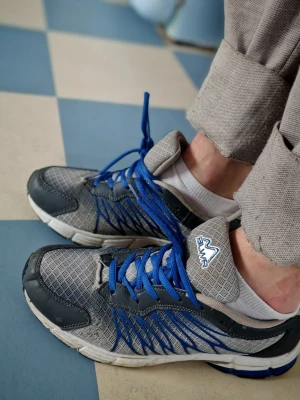 Gråa BLWR sneakers med blå detaljer - Snygga sneakers i grå mesh med blå detaljer och blå skosnören. Skorna har vita sulor och svarta förstärkningar vid tån och hälen. Perfekta för dig som gillar sportig stil och vill sticka ut med coola dealjer. Skorna har en viss retro look. 