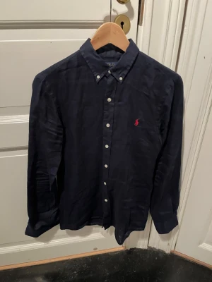 Blå Ralph Lauren skjorta - Säljer en mörkblå linneskjorta från Ralph Lauren. Perfekt till sommaren! Den är i storlek S