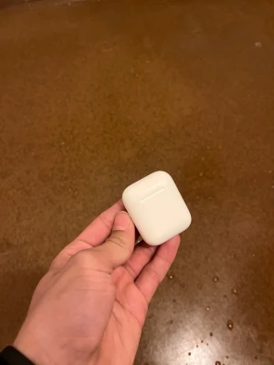 Vita trådlösa hörlurar med laddningsetui - Säljer ett par vita trådlösa hörlurar med tillhörande laddningsetui. Etuiet är kompakt, rektangulärt och har en slät yta i plast. Perfekt för dig som vill ha smidiga hörlurar till mobilen eller datorn.