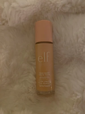 e.l.f. Halo Glow Liquid Filter foundation - e.l.f. Halo Glow Liquid Filter foundation i en glasflaska med persikofärgat lock. Flytande formula som ger glow och lyster till huden. Flaskan rymmer 31,5 ml och har en stilren design med vit text på framsidan. Perfekt för dig som vill ha en naturlig, strålande finish. I shade 1💕 helt oandvänd, bara öppnad❤️