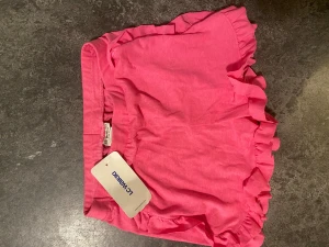 Rosa volangshorts från LC Waikiki - Snygga rosa shorts från LC Waikiki med volangdetaljer längs benen. Perfekta för varma dagar och har en bekväm passform med elastisk midja. Gjorda i mjuk bomull som känns skön mot huden. För barn storlek 11-12 år 