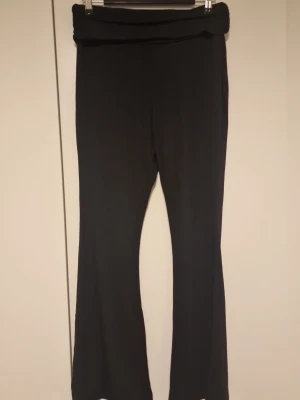  Svarta bootcut leggings - Säljer ett par svarta leggings med bootcut-modell och bred linning i midjan. De är stretchiga och bekväma, perfekta till både oversized tröjor och crop tops. Materialet känns mjukt och följsamt, men inget märke syns på plagget.