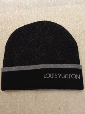 Svart mössa med logga - Snygg svart mössa. Perfekt accessoar för att lyfta din stil under kyliga dagar. Ej använd