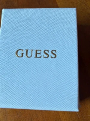 Blommiga örhängen från Guess - Snygga örhängen från Guess i guldfärgad metall med blommig design. Örhängena har små gnistrande stenar som ger en elegant touch. Perfekta för dig som vill ha något trendigt och stilrent från ett välkänt märke.