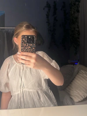 Vit puffärmad blus med rund hals - Söt vit blus med puffiga korta ärmar och rund halsringning. Blusen har en lätt rynkad design och är tillverkad i ett tunt, luftigt material som ger en romantisk känsla. Perfekt att styla med jeans eller kjol.