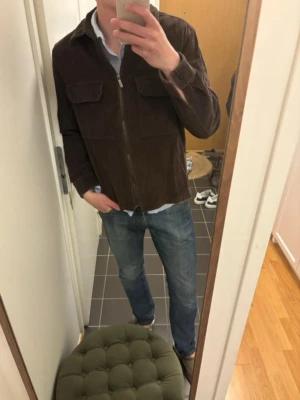 Brun manchester overshirt Strömberg - Säljer en brun overshirt i manchester från Strömberg. Skjortjackan har två stora bröstfickor med lock, dragkedja framtill och klassisk krage. Perfekt lager på lager-plagg för dig som gillar en avslappnad men stilren look.