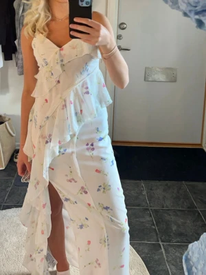Vit blommig långklänning Gina Tricot - En fin lång klänning med slits från Gina tricot. Perfekt till midsommar. Använd 1 gång 