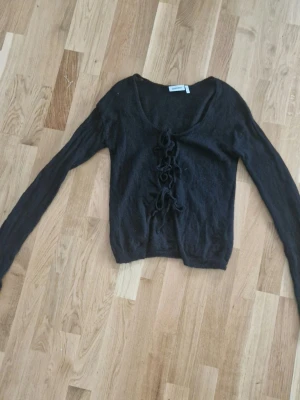 Svart tunn kofta - Använd men i bra skick. Har långa ärmar. Kan bäras åt båda hållen. Seethrough material. 50% ull.