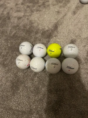 7 Titleist golfbollar, en gul - Säljer ett set med 67 golfbollar från Titleist, varav 6 är vita och 1 är gul. Bollarna har olika nummer och märkningar som Tour Soft och TruFeel. Perfekt för dig som vill fylla på golfbagen med kvalitetsbollar.