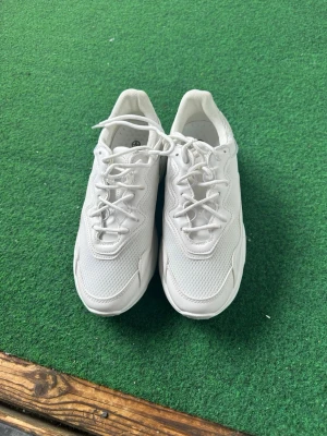 Vita chunky sneakers i mesh - Säljer ett par vita chunky sneakers med meshdetaljer och vågiga sömmar. Skorna har tjock sula och snörning framtill. Perfekta för dig som gillar en clean och sportig look. Materialet är en mix av syntet och mesh för extra komfort.