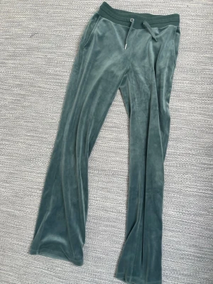 Gröna velour mjukisbyxor med fickor - Mysiga gröna mjukisbyxor i velour med bred resårmidja. Ett av snörena saknar en metall grej i slutet men annars bra skick.