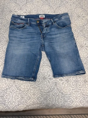 Blue Denim Tommy Jeans - 33 - Säljer ett par klassiska blå jeansshorts från Tommy Jeans. Storlek 33. Herr. Säljes för 150kr, nypris ca 600kr.