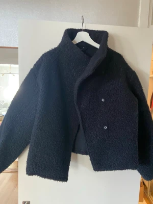 Marinblå teddyjacka med hög krage - Mysig marinblå  teddyjacka med hög krage och dubbelknäppning framtill. Obetydligt använd. Stl M från Gina Tricot