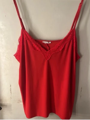 linnetoppar med spetsdetaljer - Säljer 3 snygga linnetoppar med tunna axelband och spets längs v-ringningen. En topp är röd och den andra är grön, båda i mjukt material som känns skönt mot huden. Perfekta att styla till jeans eller kjol för en trendig look.