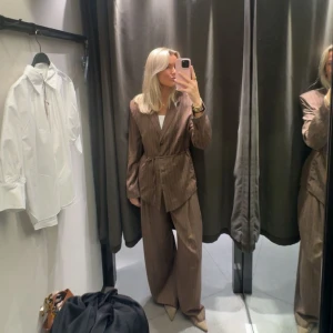Brun kostym från Zara!🤎 - Snygg brun kostym med diskreta kritstrecks ränder, består av kavaj med knyt i midjan och matchande vida byxor. Kavajen har klassisk krage och långa ärmar, byxorna är höga i midjan och har en loose passform. Endast använda ett fåtal gånger!🤎
