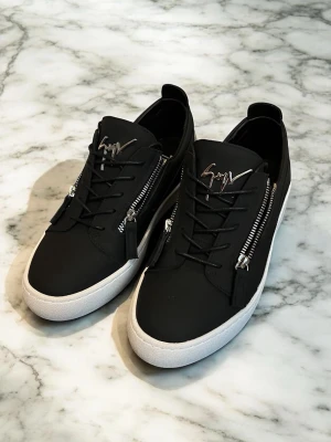 Giuseppe Zanotti - Snygga svarta sneakers från Giuseppe Zanotti med vita sulor, silverfärgade dragkedjor på sidorna och logga på plösen. Skorna har snörning och detaljer i blankt material vid hälen. Perfekta för dig som gillar stilrena och exklusiva sneakers.