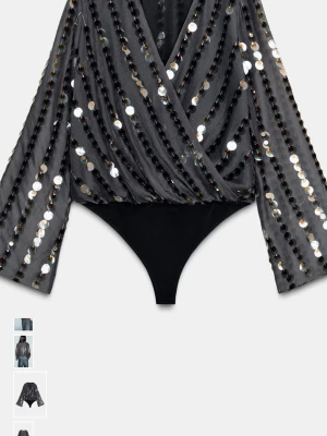 Zara topp - Snygg svart body med transparent mesh och stora silverfärgade paljetter i diagonala rader. Djup omlott-ringning och vida ärmar ger en trendig look. Perfekt för dig som vill sticka ut. Materialet är lätt och stretchigt, vilket gör den bekväm att bära.