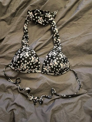 Mörkblå blommig bikiniöverdel med knyt - Supersnygg mörkblå bikiniöverdel med små vita och rosa blommor. Halterneck-modell med breda band som knyts i nacken och baktill. Perfekt för sommaren. Är i storlek xs men skulle säga att den även passar S. Skriv gärna frågor 💗